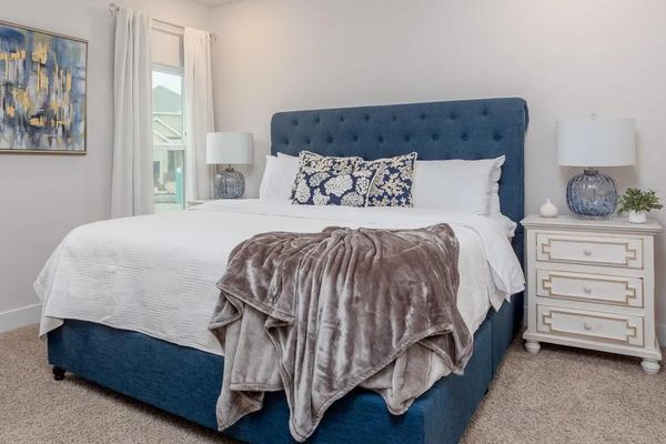 Cozy bedroom with a blue upholstered bed and soft gray throw blanket.