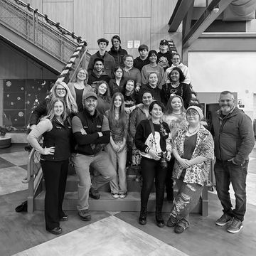 Group photo of diverse people on stairs indoors.