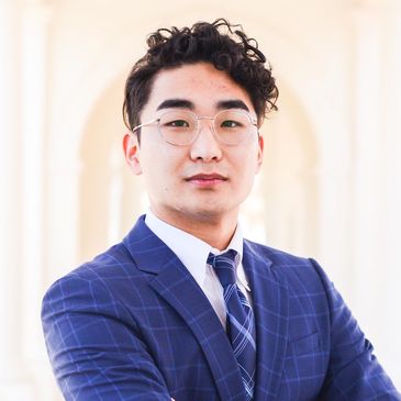 Confident young man in a blue suit and glasses.