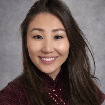 Smiling woman with long dark hair and a sequined burgundy top.