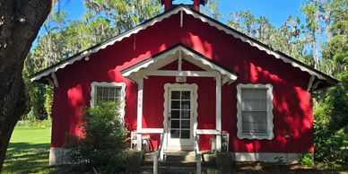 A charming red building with white trim and a small bell tower under a clear blue sky.