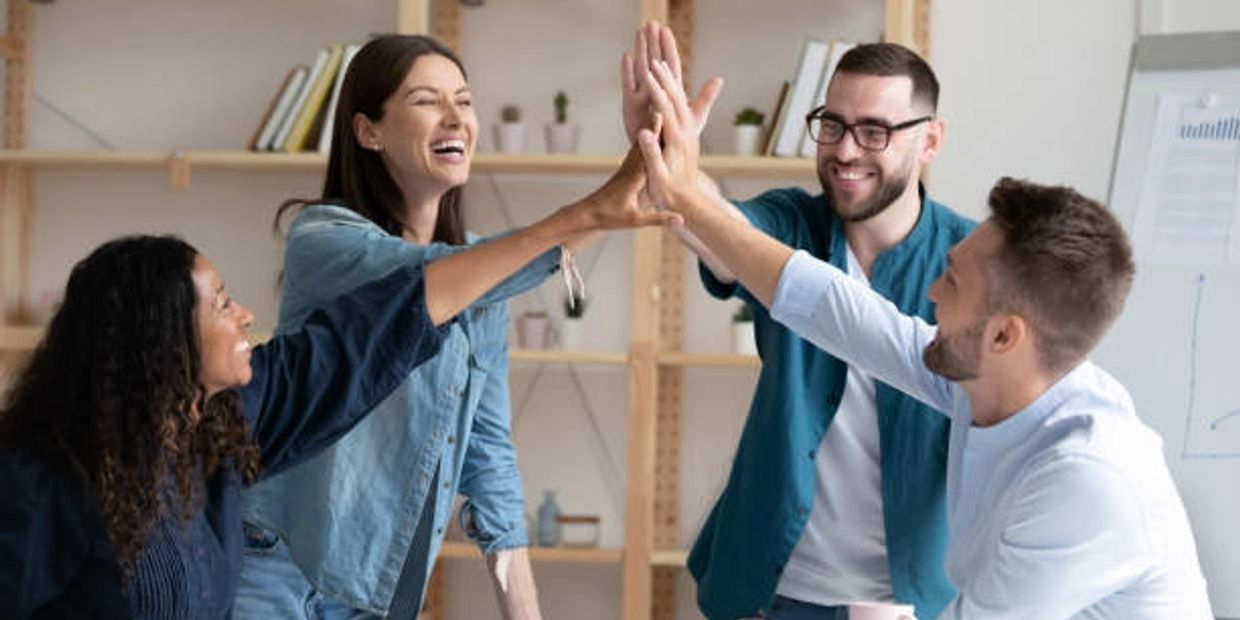 Jóvenes juntando las manos en señal de éxito laboral