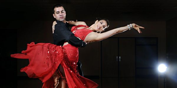 A couple elegantly dancing, woman in a flowing red dress.