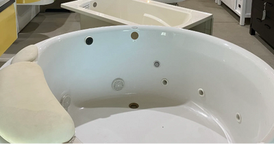 A luxurious white free standing tub sits on a tiled floor.