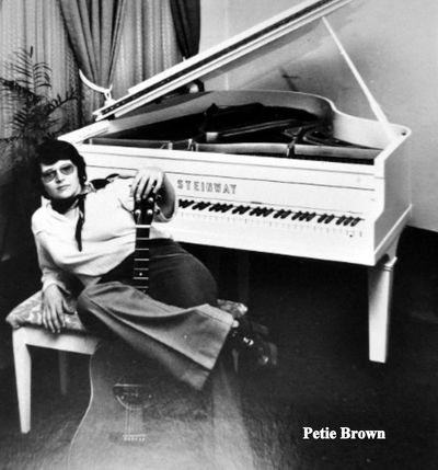 Young Peter Brown reclining in front of a grand piano.