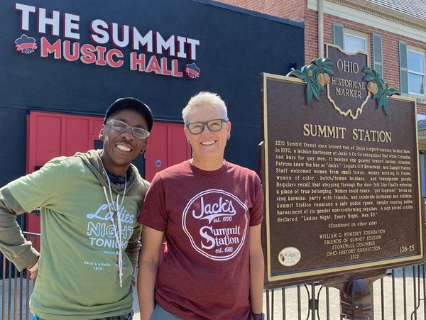 Two people smiling in front of The Summit Music Hall and a historical marker in Ohio.