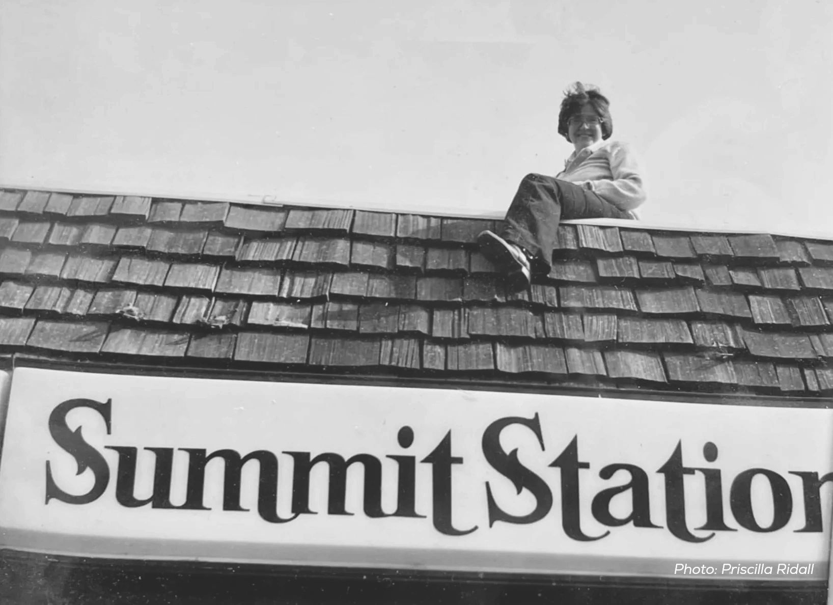 A black and white photo of Peter Brown sitting on the roof of Summit Station.