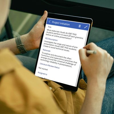 Person writing project details on a tablet.