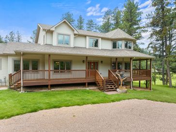 Large two-story house with a wraparound porch and a carved bear statue on the steps.