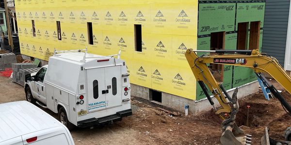 Construction site with yellow sheathing and white utility trucks.