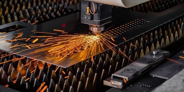 Laser cutting metal sheet with sparks flying.