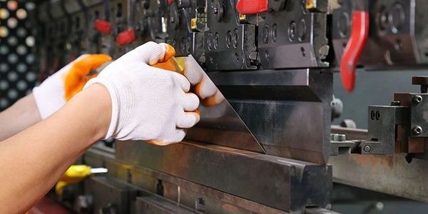 Worker operating a sheet metal bending machine.