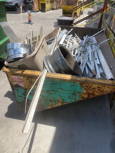 A rusty dumpster filled with various metal scraps and debris outdoors.