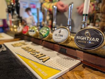 Close-up of beer taps with various brand logos at a bar counter.