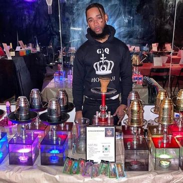 Man standing behind a table with hookahs and accessories at a display booth.