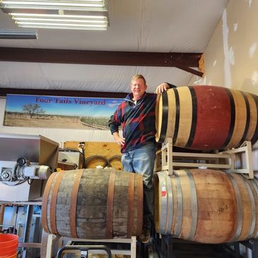 Owner standing on wine barrels.