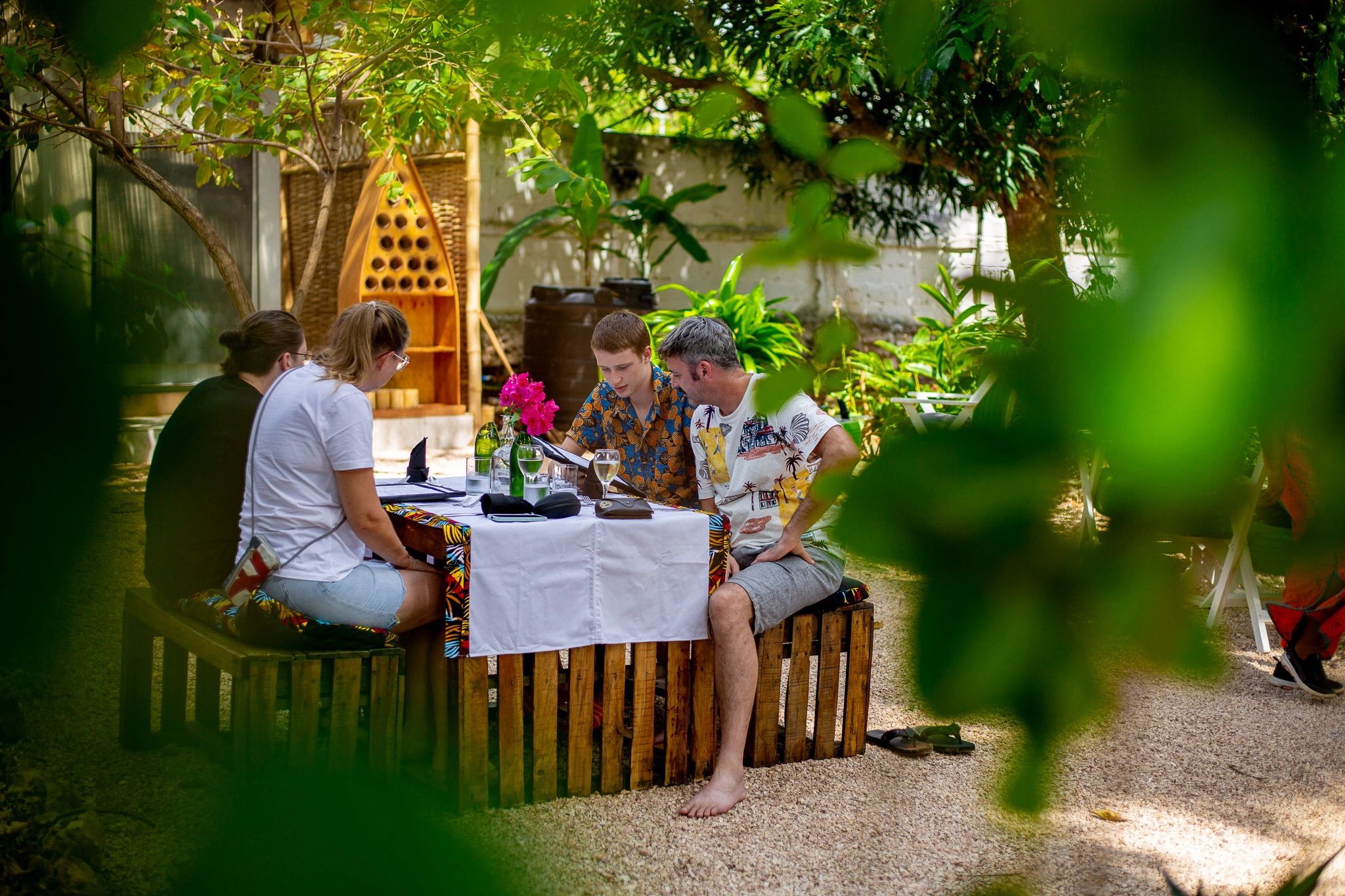 family of four seated at a table while on their zanzibar vacation. they are reading the menu