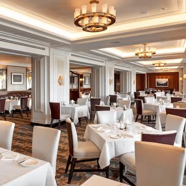 Elegant, well-lit restaurant dining area with white tablecloths and comfortable seating.