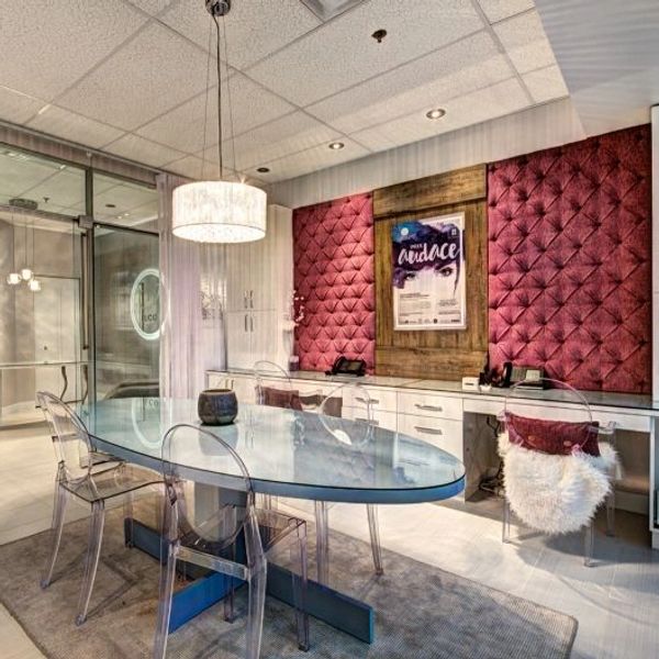 Modern meeting room with glass table and transparent chairs under chandelier.