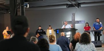 A group performs music at a church service with an audience watching.