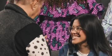 A smiling woman with glasses interacting with another person.