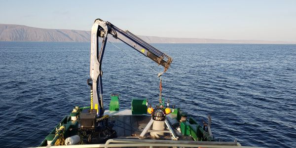 Research vessel deploying underwater equipment into the sea.