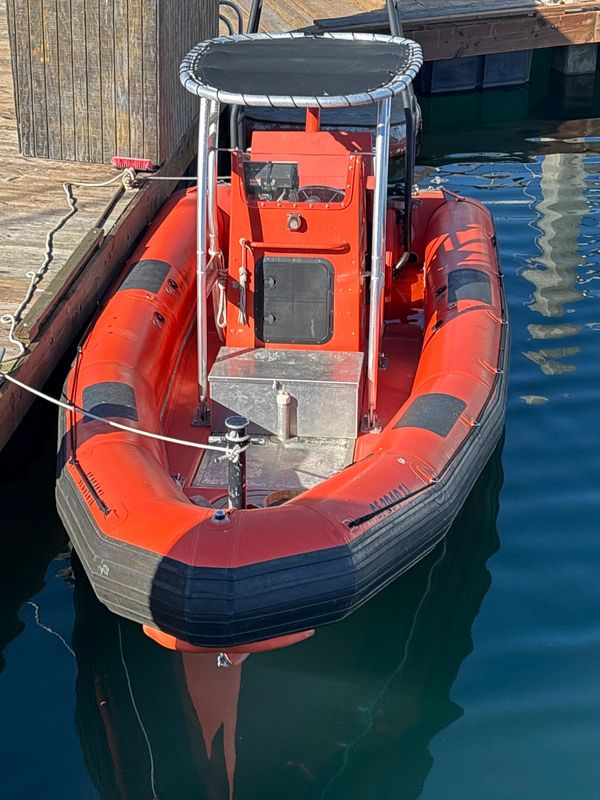 Red inflatable boat docked at a wooden pier.