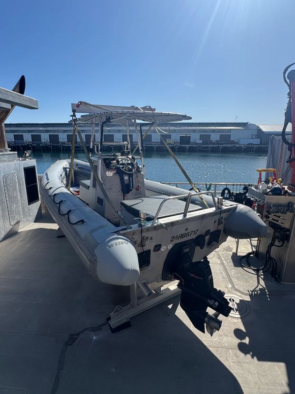 Rigid inflatable boat docked on a sunny day by the water.