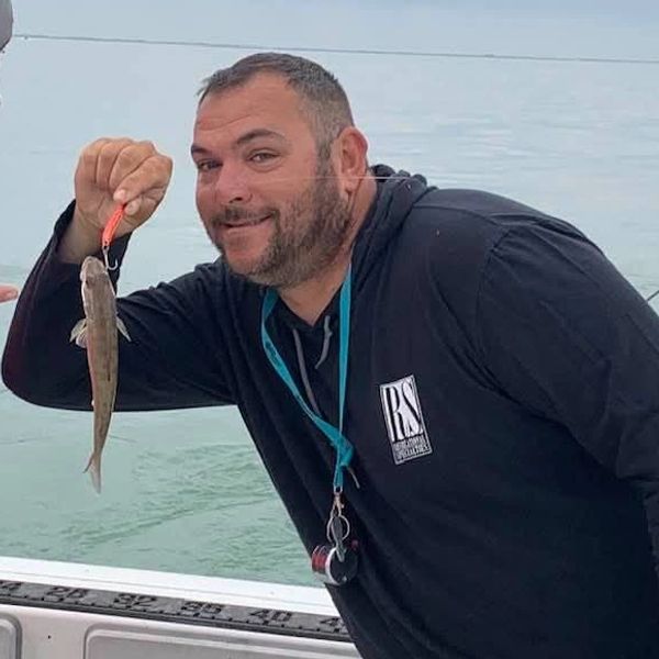 Captain Dave Borzeniatow holding a tiny Walleye. 