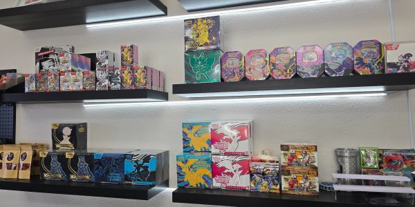 Shelves displaying colorful collectible card game boxes and tins.