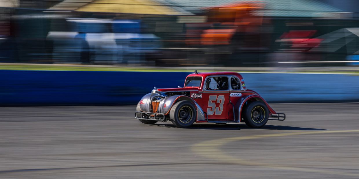 Red vintage race car number 53 speeding on a race track.