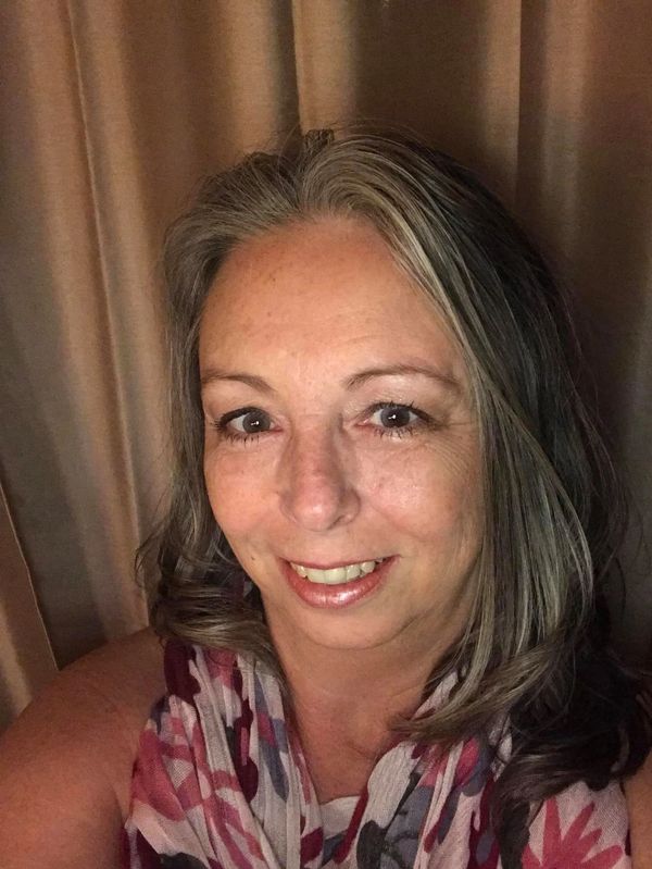 Woman smiling for a selfie with curtain backdrop.
