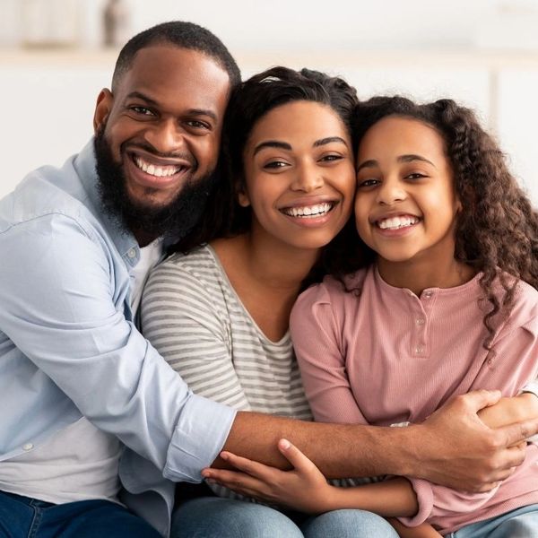 Smiling family of three sharing a warm embrace at home.