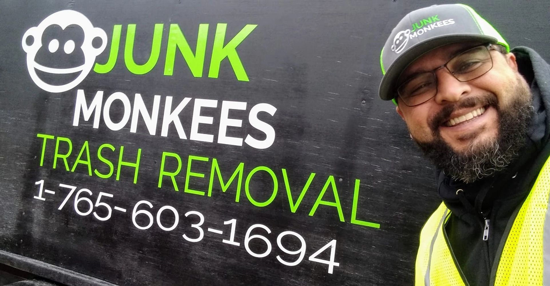 Junk Monkees trash removal owner smiling next to company logo in Marion Indiana.