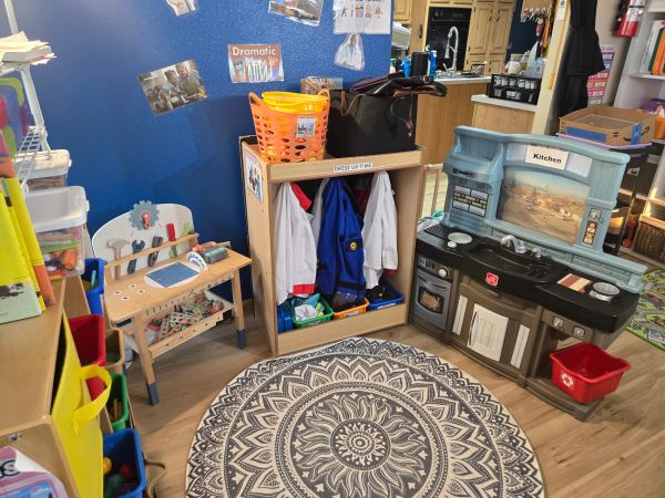Children's play and dress-up area with toy kitchen and costumes.