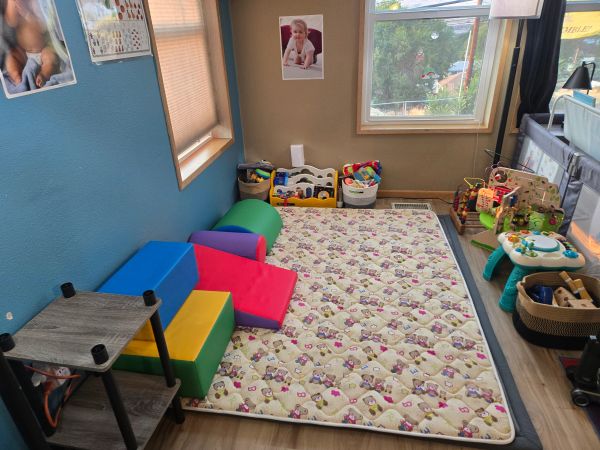 A colorful children's playroom corner with toys and cushions.