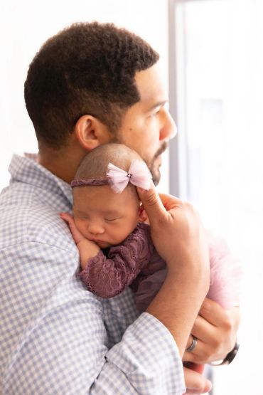 Father holding his sleeping baby girl gently.