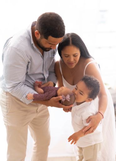Parents introduce baby to toddler in a warm setting.