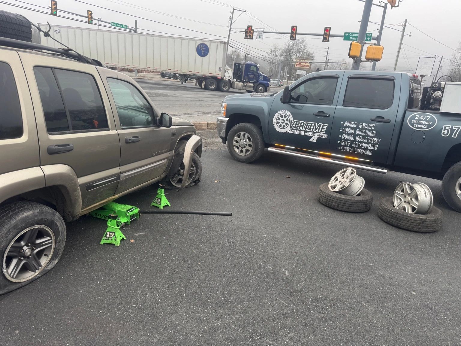 Roadside technician replacing multiple wheels on a disabled SUV with a service truck