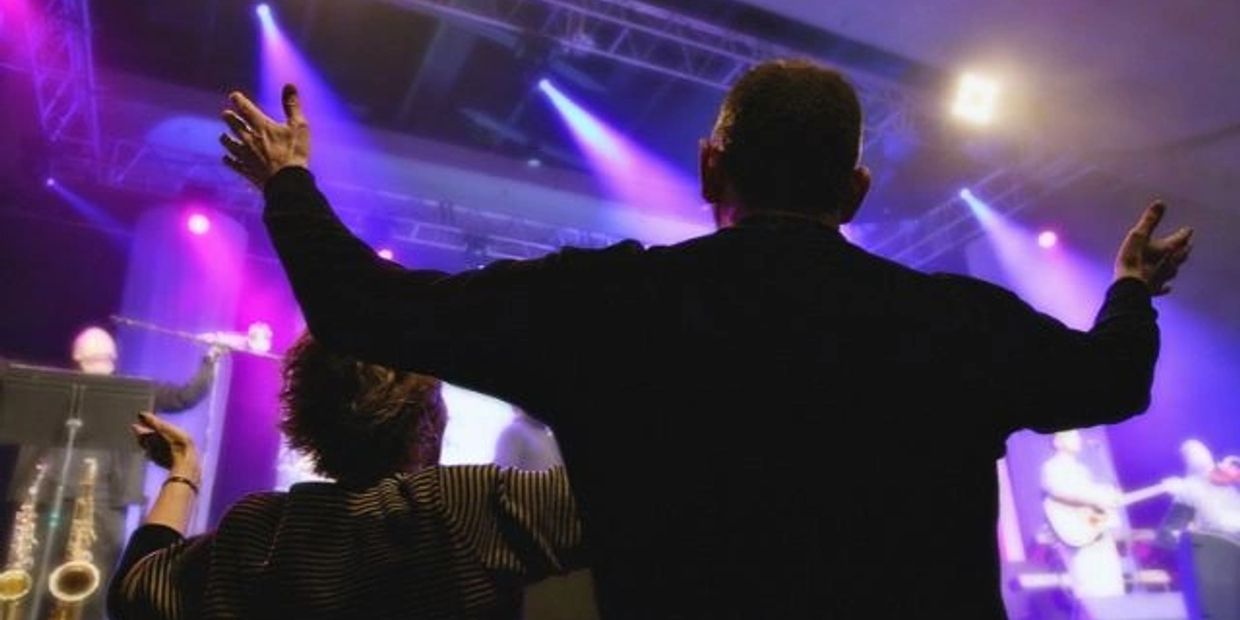 People enjoying a concert with purple stage lighting.