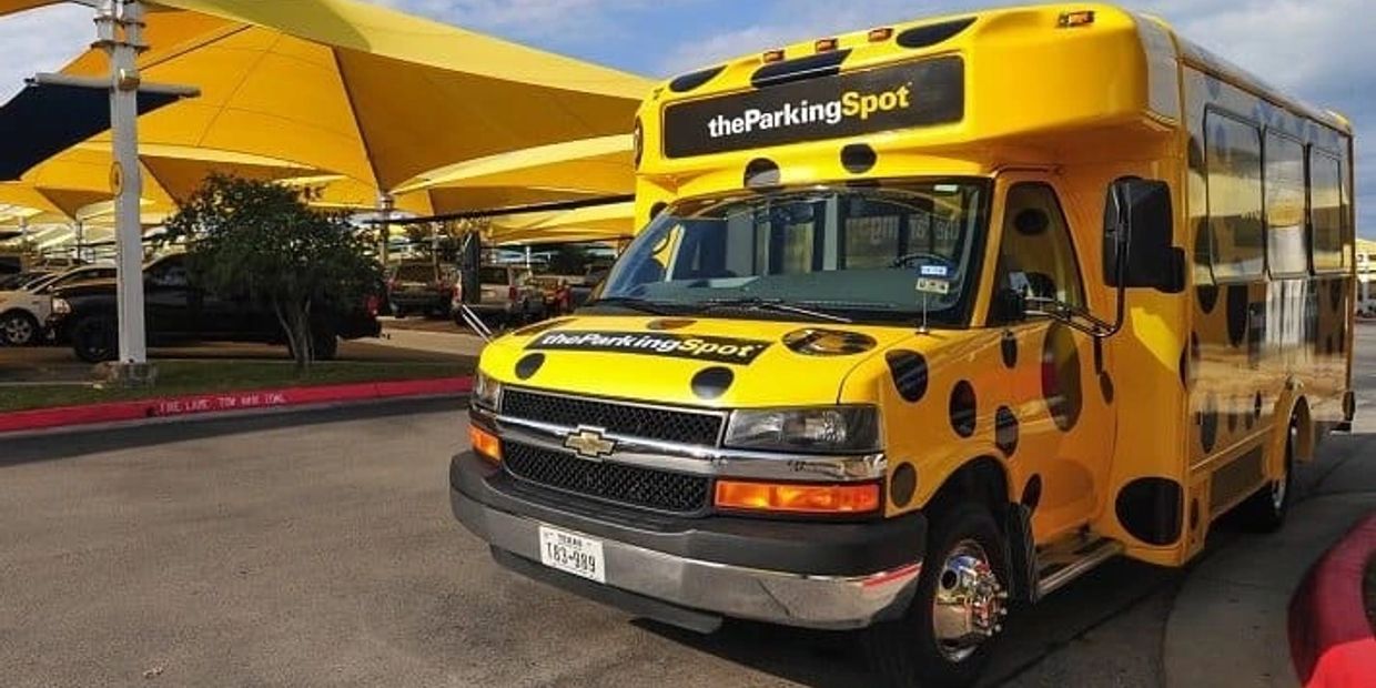 Yellow shuttle bus with black spots parked in a lot.