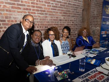 Group of five women at a conference or event table.