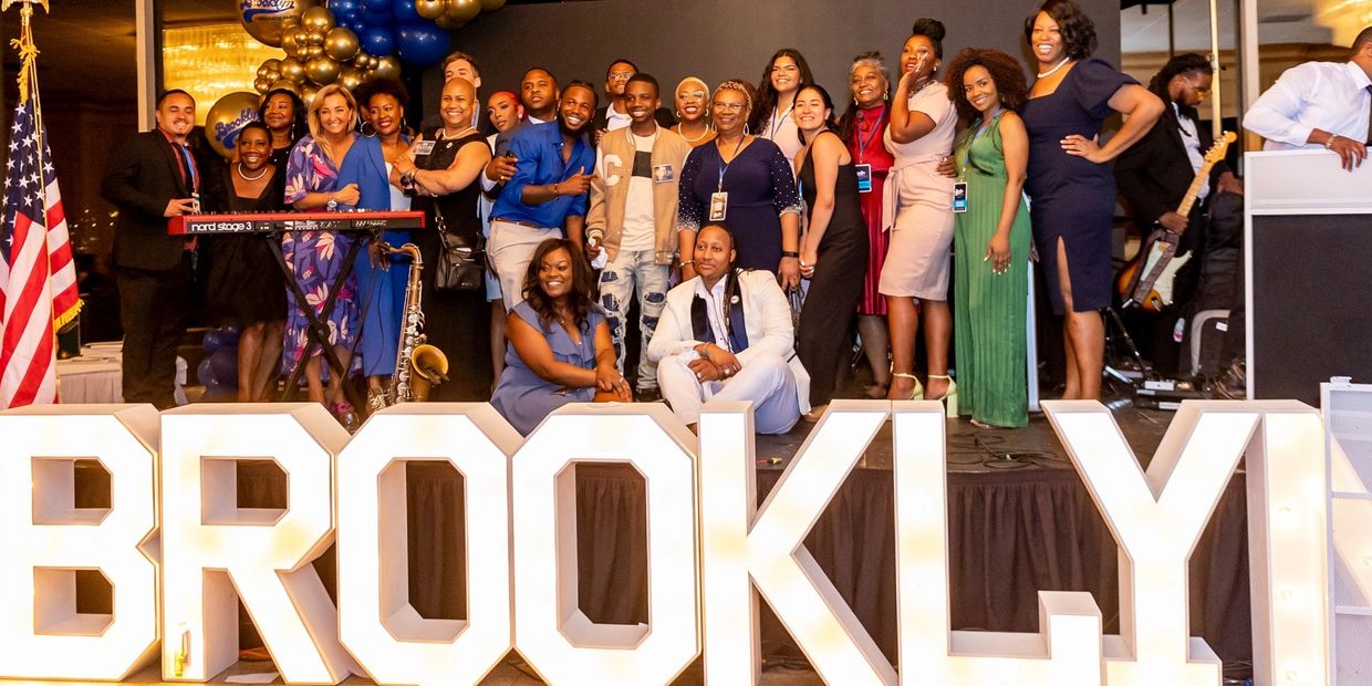 Group photo at a Brooklyn event with large illuminated letters.