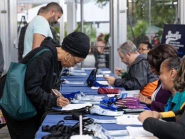 Woman signing paperwork at event registration table.