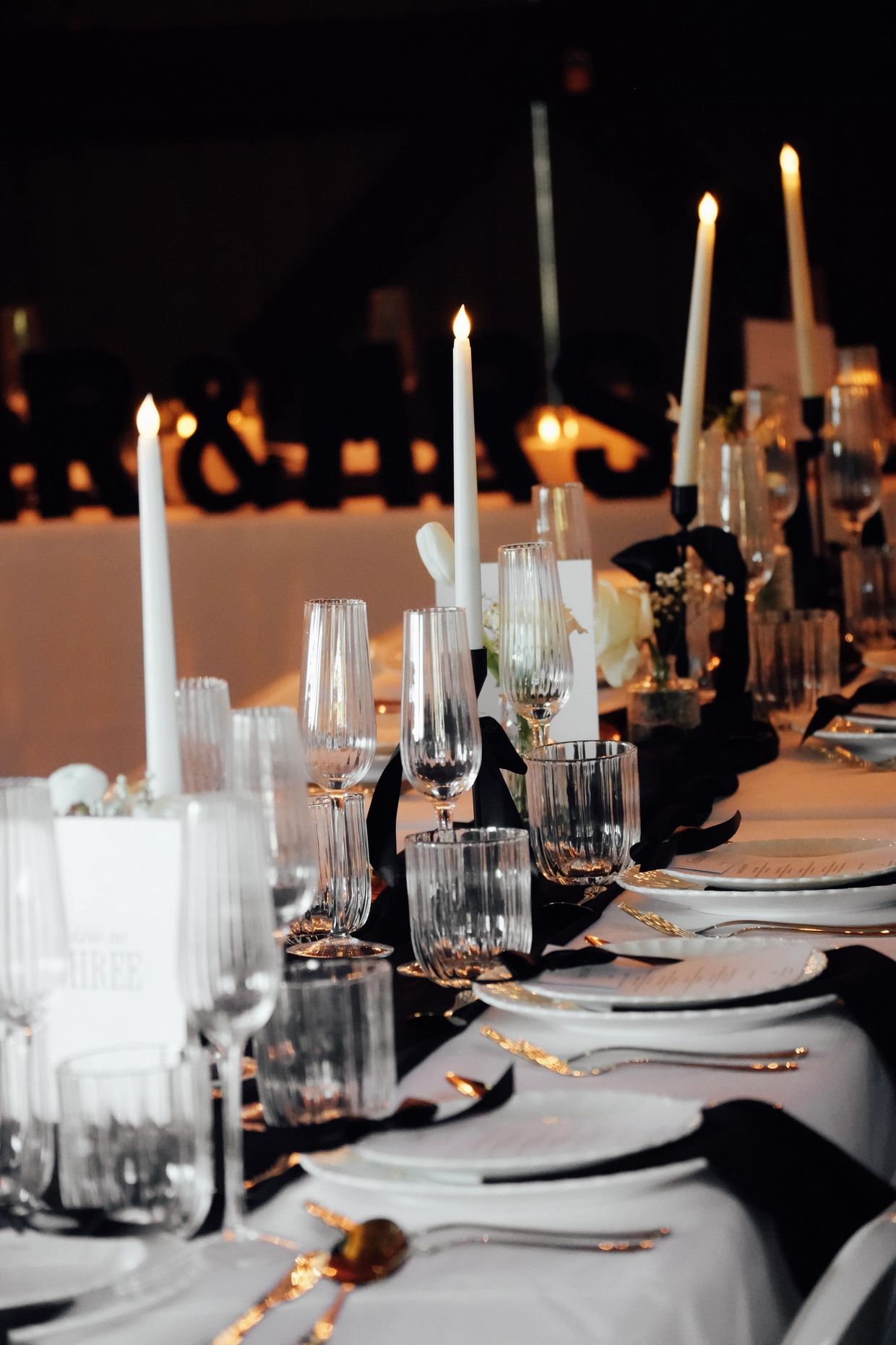 Elegant black and white reception table, all set with plates & gold cutlery 
