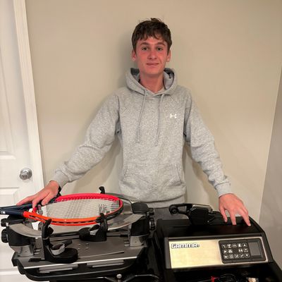 Young man with tennis racquet stringing machine indoors.