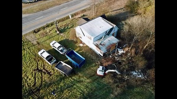 Aerial view of a house with construction vehicles and debris nearby.