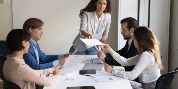 Woman distributing papers to colleagues in a meeting.