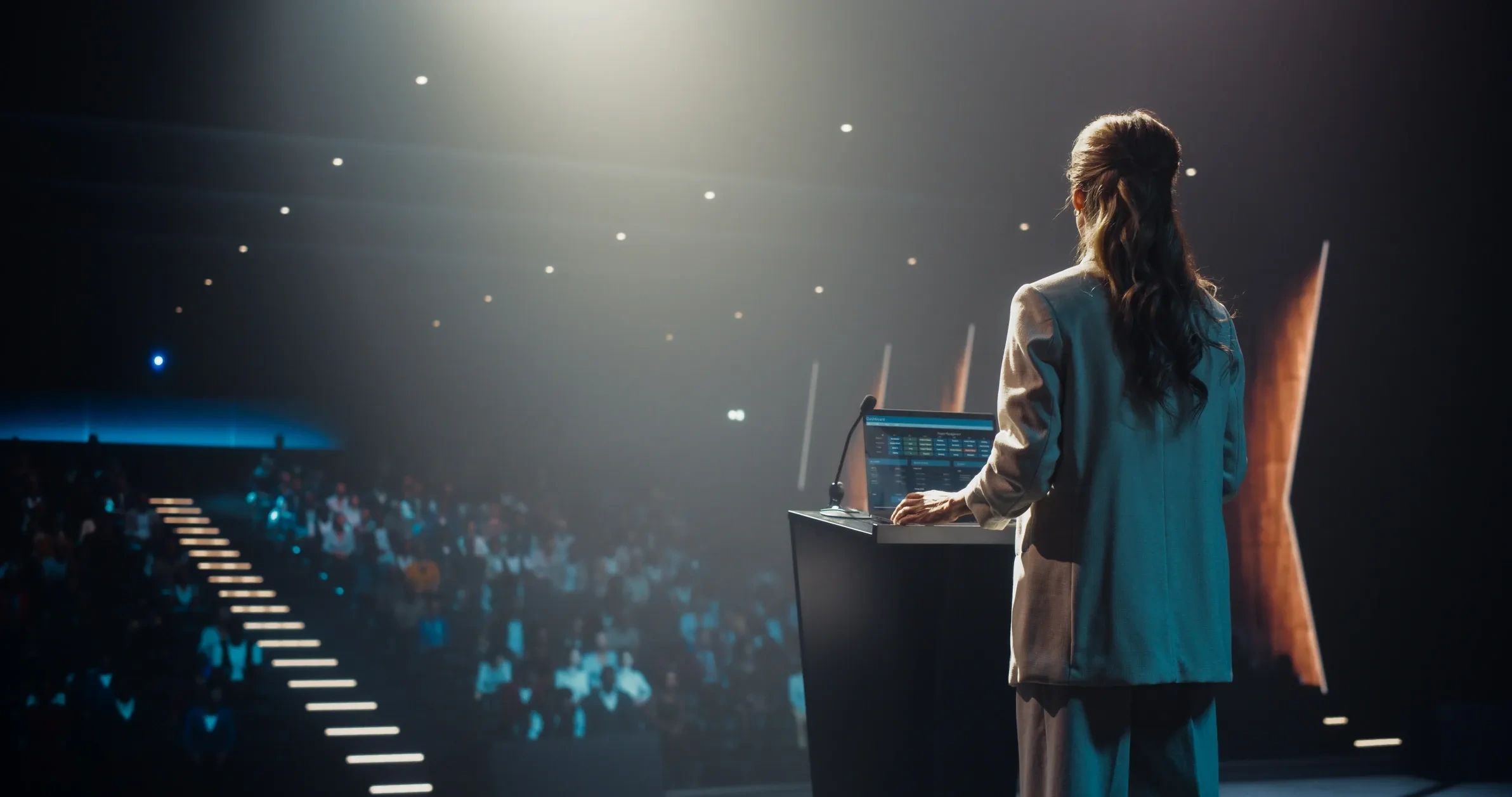 Woman presenting at a conference in front of a large audience.