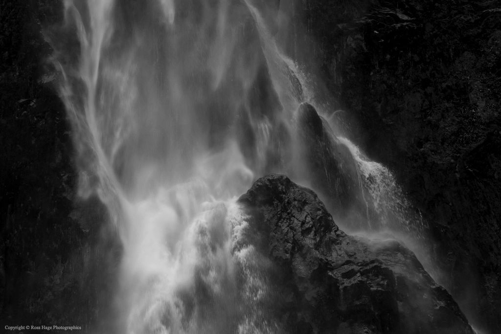 Black and white image of water cascading over rocks in a waterfall.